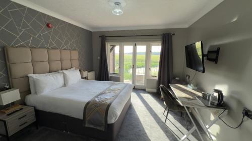 a bedroom with a bed and a desk and a television at Dolphin Hotel St Ives in St. Ives