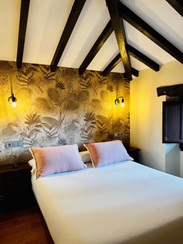 a bedroom with a large white bed with two pillows at La Casina de la Arquera in Llanes