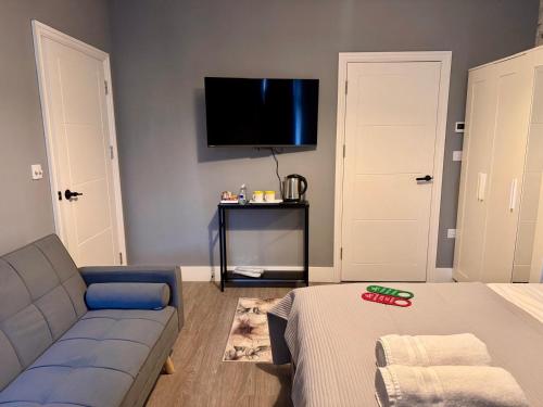 a living room with a couch and a flat screen tv at 40th Avenue Guest House in Mill Hill