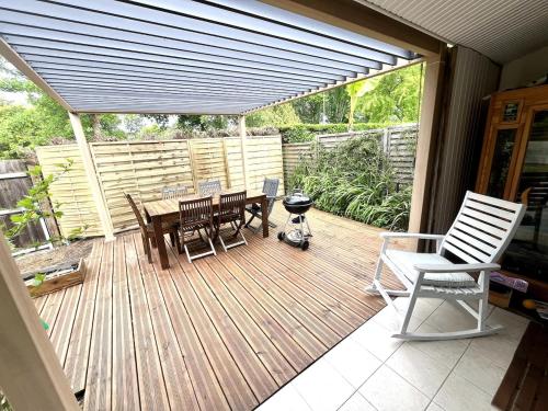 a wooden deck with a table and chairs and a grill at Surf, Skate, Golf house Seignosse in Seignosse