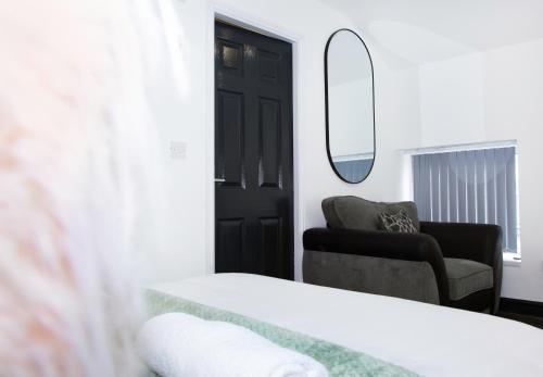 a bedroom with a bed and a mirror and a chair at Snuggle Cove Apartments- Walton Road in Liverpool