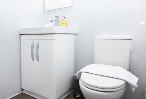a white bathroom with a toilet and a sink at Snuggle Cove Apartments- Walton Road in Liverpool