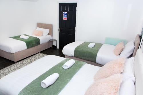 a room with three beds with towels on them at Snuggle Cove Apartments- Walton Road in Liverpool