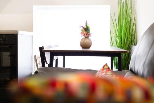 a table with a vase on top of it next to a couch at Snuggle Cove Apartments- Walton Road in Liverpool