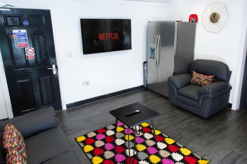 a living room with a couch and a table and a refrigerator at Snuggle Cove Apartments- Walton Road in Liverpool
