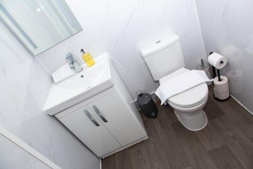 a white bathroom with a toilet and a sink at Snuggle Cove Apartments- Walton Road in Liverpool