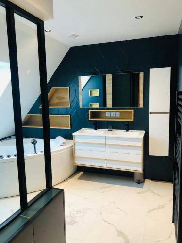 une salle de bain avec un lavabo, une baignoire et un miroir dans l'établissement Le petit Alice cottage, à Cléder