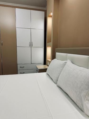 a bedroom with a white bed and a closet at Korca Apartment in Korçë