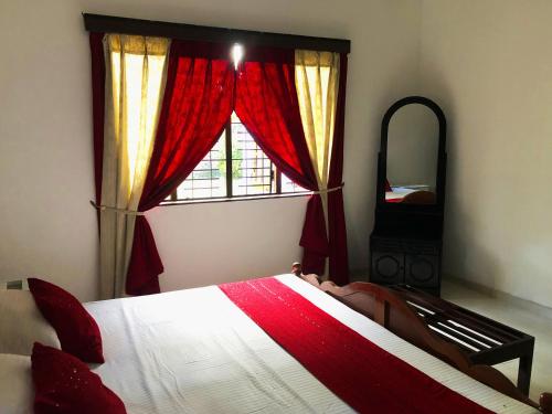 a bedroom with a bed and a window with red curtains at Hotel Happy Vibes in Galle