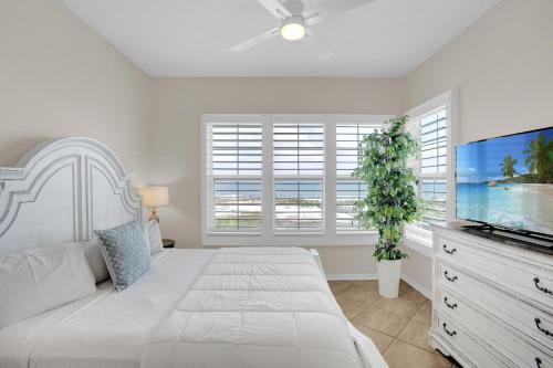 a white bedroom with a large bed and a flat screen tv at 305 West in Gulf Highlands