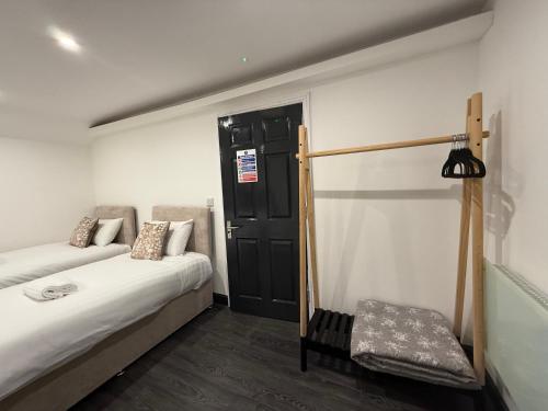 a bedroom with two beds and a black door at Snuggle Cove Apartments- Walton Road in Liverpool