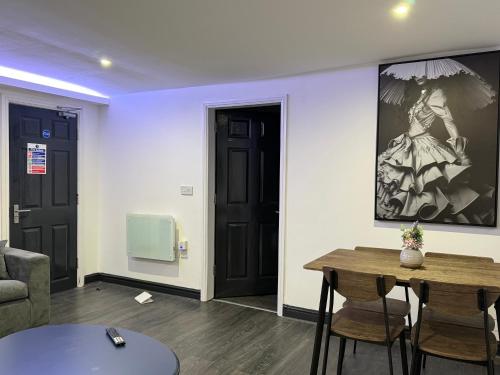 a living room with a table and chairs and a painting at Snuggle Cove Apartments- Walton Road in Liverpool