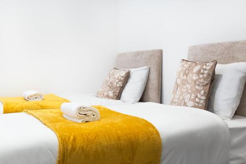 two beds with yellow and white sheets and pillows at Snuggle Cove Apartments- Walton Road in Liverpool