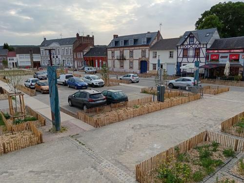 a town with cars parked in a parking lot at Gite 6 à 8 personnes in Gamaches