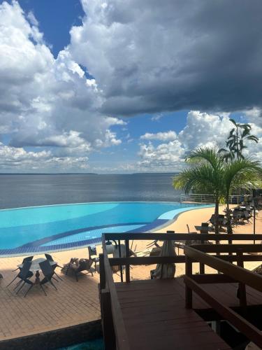 a view of a swimming pool with chairs and the beach at Flat Tropical in Manaus