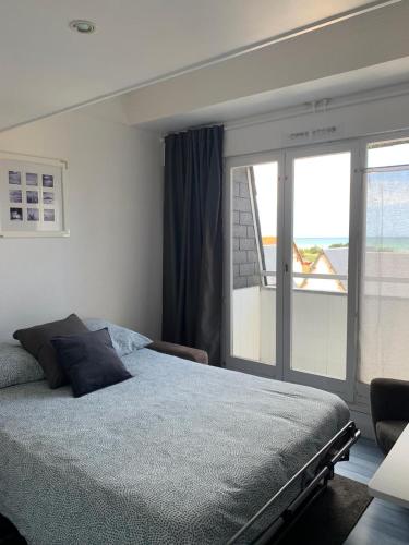 une chambre avec un lit et une grande fenêtre dans l'établissement Blue, studio avec vue mer et matelas en mezzanine, à Courseulles-sur-Mer