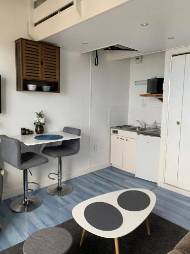 une cuisine avec une table et des chaises dans une pièce dans l'établissement Blue, studio avec vue mer et matelas en mezzanine, à Courseulles-sur-Mer