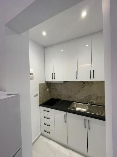 a kitchen with white cabinets and a sink at Vila Ori in Ksamil