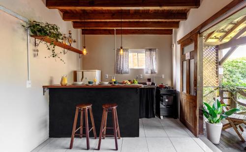 a kitchen with a black counter and two stools at Moradas do Vale Praia do Rosa in Praia do Rosa