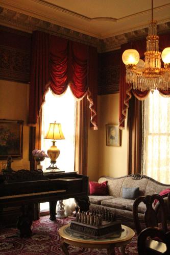 a living room with a piano and a couch at Henderson Castle Inn in Kalamazoo