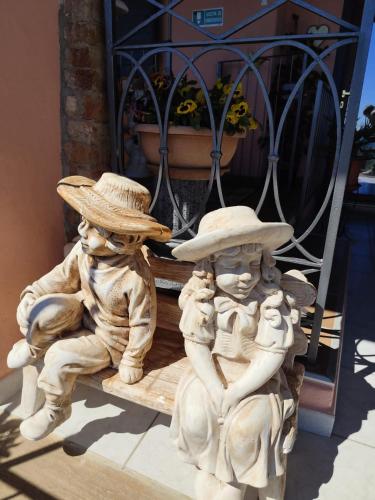 a statue of three people wearing hats sitting on a bench at affittacamere La Betulla in Pettinengo