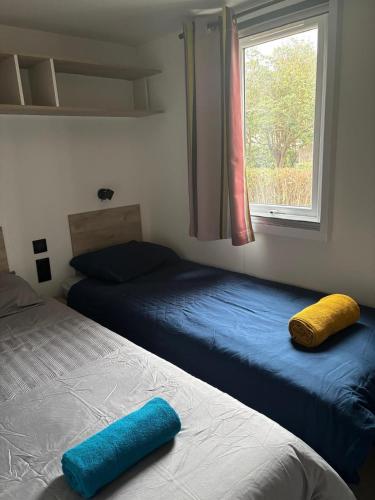 une chambre avec deux lits et une fenêtre dans l'établissement Mobil-home les pieds dans l'eau camping les dunes, à Torreilles