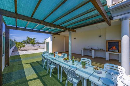 a long table and chairs on a patio with a fireplace at Villa Casa Grande by Villa Plus in Albufeira