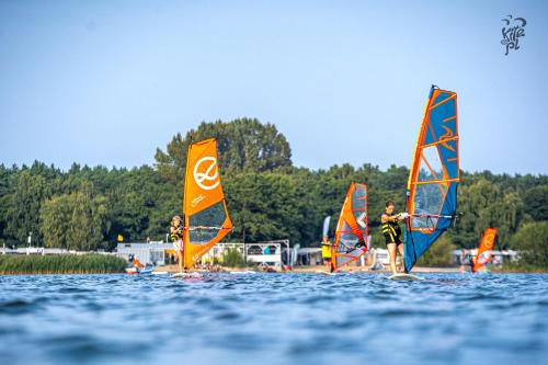 un gruppo di persone che fanno windsurf sull'acqua di Chalëpë 20 całoroczne, komfortowe domki "Tiny House" a Chałupy