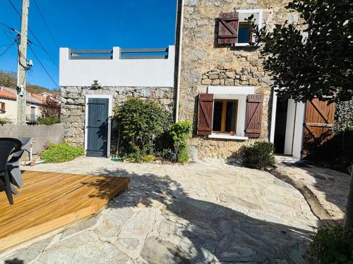 une maison en pierre avec une terrasse en bois devant elle dans l'établissement Belle maison de montagne proche Ajaccio, à Bastelica