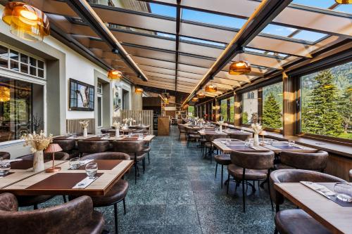 a restaurant with wooden tables and chairs and windows at Le Saint Georges in Gruyères
