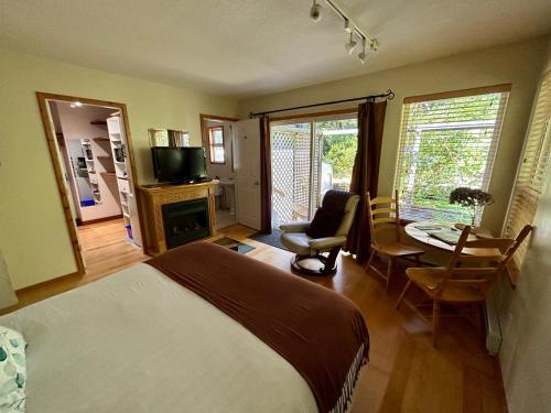 a bedroom with a bed and a table with a chair at Cobble Wood and Bird Sanctuary Guest Houses in Tofino