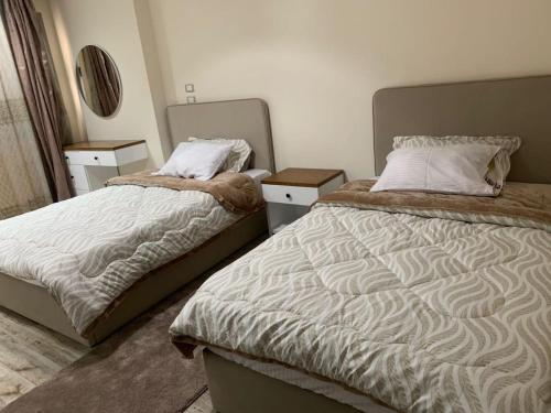 a bedroom with two beds and two night stands at H Flat With Roof- One Kattamya in Cairo