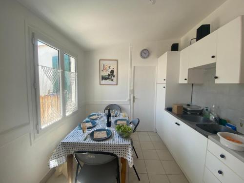 een keuken met een tafel met een tafelkleed erop bij Départ du Marin à la Cotinière in Saint-Pierre-dʼOléron