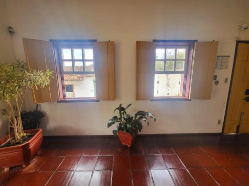 a room with three windows and potted plants at Pousada Do Ó in Tiradentes