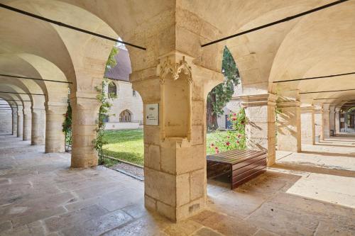a stone archway with a bench in a courtyard at Appart'hôtel Odalys City - Dijon Centre Les Cordeliers in Dijon