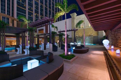 a hotel lobby with tables and chairs and palm trees at Londoner Grand, a Luxury Collection Hotel, Macau in Macau