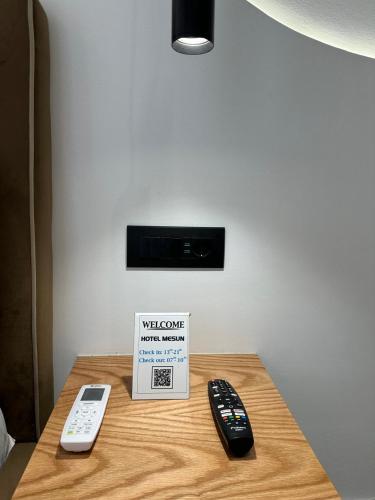 two remote controls and a sign on a table at Hotel Mesun Himare in Himare