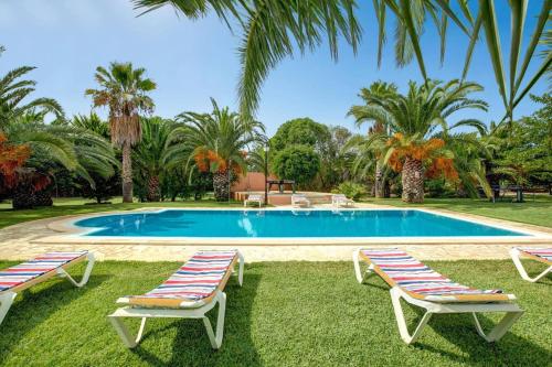 a swimming pool with two lounge chairs in the grass at Villa Marino by Villa Plus in Cala d´Or
