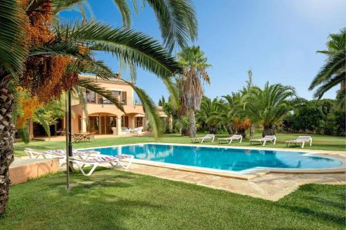 a villa with a swimming pool and palm trees at Villa Marino by Villa Plus in Cala d´Or