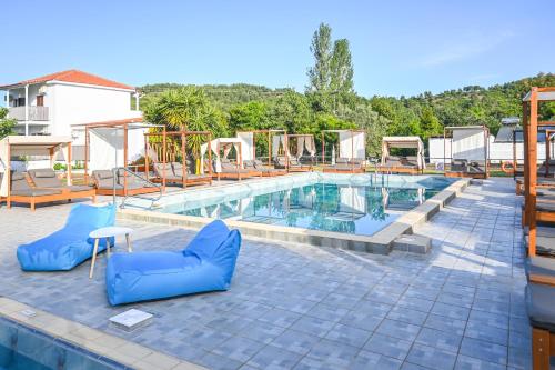 a large swimming pool with blue chairs next to it at Giabeos Skiathos in Troulos