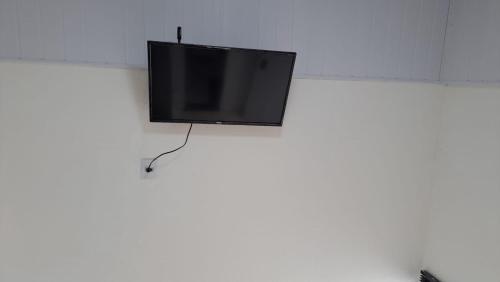 a flat screen tv hanging on a white wall at Pousada do sol in Sorocaba