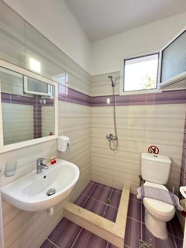 a bathroom with a white sink and a toilet at Hotel Mesun Himare in Himare