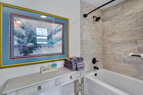 bagno con vasca e doccia con quadro di Garden Cottage 71 a Jekyll Island