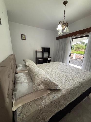 a bedroom with a bed with pillows and a window at Casa do Sítio Palmeira - Pomerode in Pomerode
