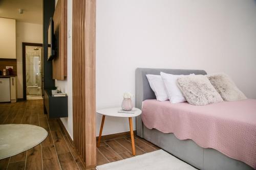a bedroom with a bed with a pink blanket and a table at POOL RESORT- Vila Lena- Studio 3 in Vrdnik