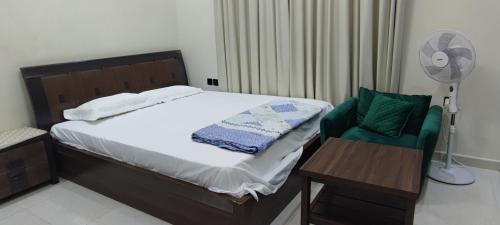 a bedroom with a bed and a chair and a fan at Villa 6 in Ajman