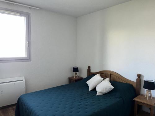 - une chambre avec un lit bleu avec des oreillers et une fenêtre dans l'établissement Résidence Hameau De Balestas Mp - T3/6pers ABELLANS 112-Peyresourde MAE-9474, à Germ