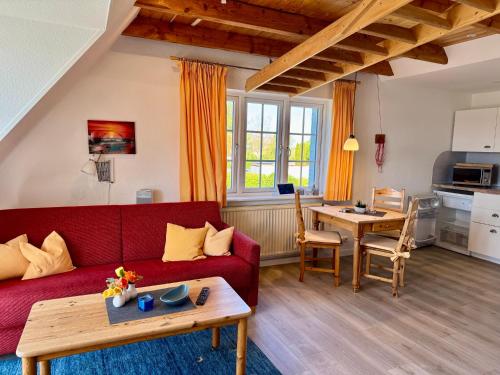 a living room with a red couch and a table at Die 5 Ferienwohnungen der Familie Weber in Fehmarn