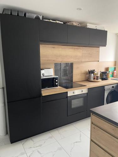 une cuisine avec des armoires noires et un four micro-ondes dans l'établissement Appartement 6 personnes, à Sète