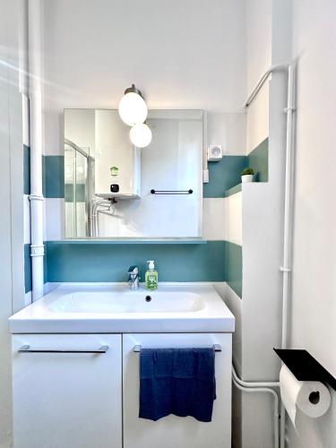 une salle de bain avec un lavabo blanc et un miroir dans l'établissement Urban Oasis Paris, à Paris